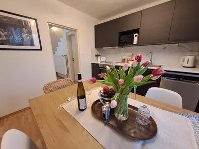 a table with a vase of flowers and a bottle of wine at Apartmánový dům se zahradou v klidné části Prahy in Prague