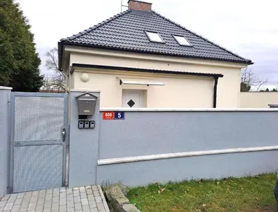 a house with a grey fence and a gate at Apartmánový dům se zahradou v klidné části Prahy in Prague
