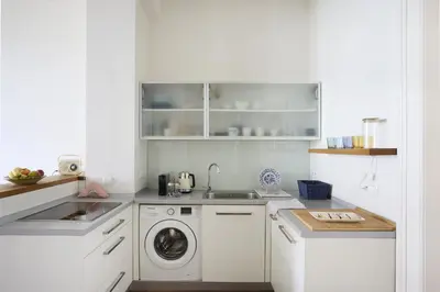 a white kitchen with a washing machine and a sink at Mama's apartment in Letna in Prague