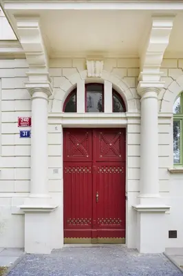 a red door on a white building with columns at Mama's apartment in Letna in Prague
