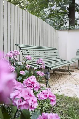 a green bench sitting next to some pink flowers at Mama's apartment in Letna in Prague