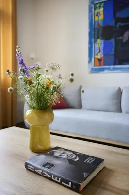 a vase with flowers on a table next to a bed at Mama's apartment in Letna in Prague