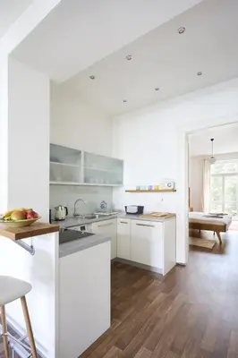 a kitchen with white cabinets and a wooden floor at Mama's apartment in Letna in Prague