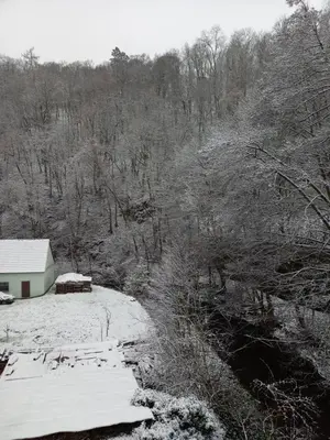 a house is covered in snow next to a river at Pod hradbami Křivoklát in Křivoklát