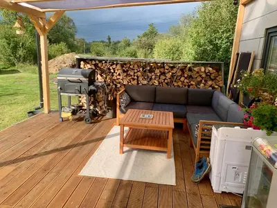 a patio with a couch and a pile of fire wood at Tiny house - Chatka v Řeži u Prahy in Husinec
