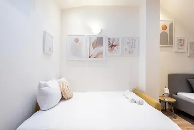 a white bedroom with a bed and pictures on the wall at B.O.B. Klimentská in Prague