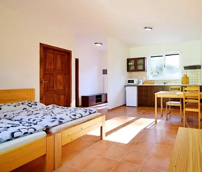 a bedroom with a bed and a kitchen with a table at Apartmán Slapy, slapská přehrada - Nová Živohošť in Křečovice