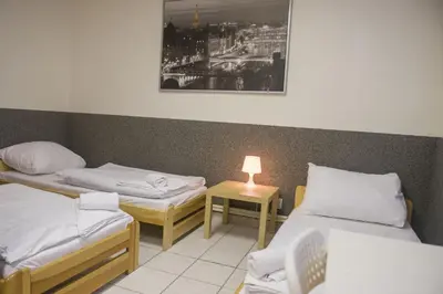 a room with two beds and a table with a lamp at Hostel Seven in Prague