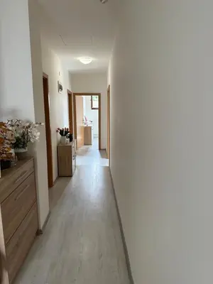a hallway with white walls and wooden floors and a white hallway at Penzion Arendel in Líšnice