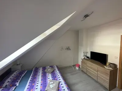 a attic room with a bed and a tv at Penzion Arendel in Líšnice