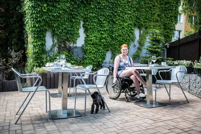 a woman in a wheelchair sitting at a table with a dog at Hotel U Karla in Prague