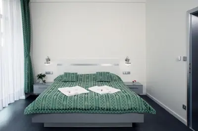 a bedroom with a green bed with two towels at Hotel U Karla in Prague