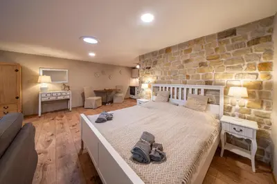 a bedroom with a bed and a stone wall at Prague West - Studio Chyne Terrace in Chýně