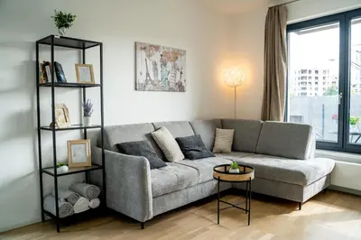 a living room with a gray couch and a window at FREE PARKING- Newly built Apartment in Prague