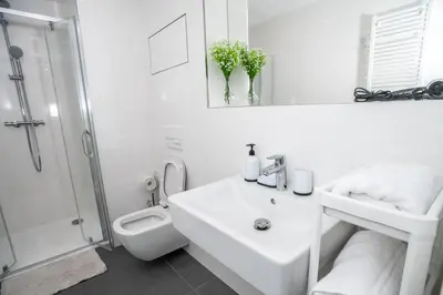 a white bathroom with a sink and a shower at FREE PARKING- Newly built Apartment in Prague