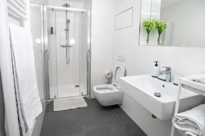 a white bathroom with a shower and a sink and a toilet at FREE PARKING- Newly built Apartment in Prague