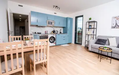 a kitchen and living room with blue cabinets and a table at FREE PARKING- Newly built Apartment in Prague