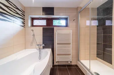 a bathroom with a tub and a glass shower at Krásné ubytování s balkonem in Prague