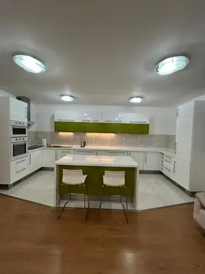 a kitchen with white cabinets and a green island at Krásné ubytování s balkonem in Prague