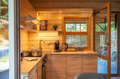 a kitchen with wooden cabinets and a stove and a window at Magic new cozy tiny house at private lake in Řehenice