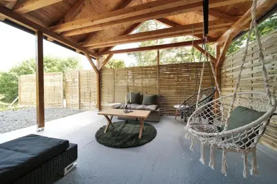 a patio with a hammock and a table and chairs at Magic new cozy tiny house at private lake in Řehenice