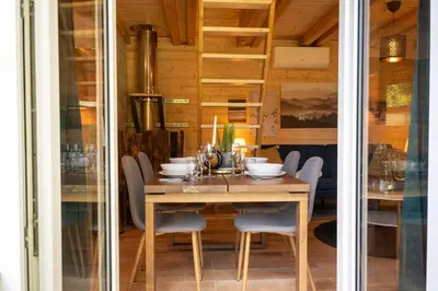 a dining room with a wooden table and chairs at Magic new cozy tiny house at private lake in Řehenice