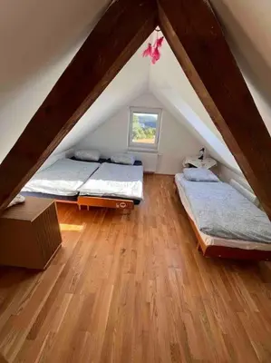 a attic room with two beds and a window at Vila v Brdech s bazénem, infra saunou a vybavením in Malá Víska