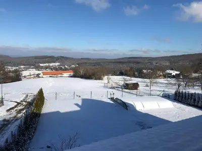 a snow covered yard with a fence and a field at Vila v Brdech s bazénem, infra saunou a vybavením in Malá Víska
