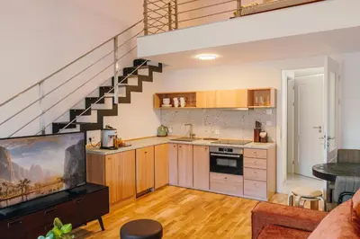 an open kitchen and living room with a staircase at Modern Mezzanine Apt at Jecna st in Prague