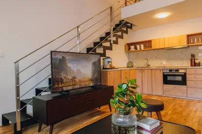 a living room with a television and a staircase at Modern Mezzanine Apt at Jecna st in Prague