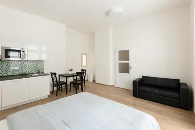 a white room with a black couch and a table at Cozy Studio in quiet courtyard near Charles Bridge in Prague
