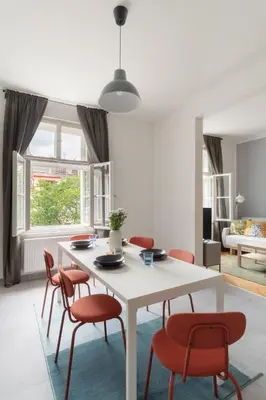 a bedroom with a bed and a chair and windows at Prague Days - Modern Apartments just 7 min from Wenceslas Square in Prague