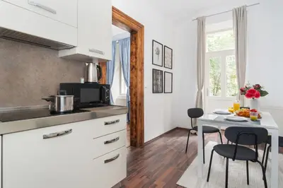 a kitchen with white cabinets and a table with chairs at Prague Days - Modern Apartments just 7 min from Wenceslas Square in Prague