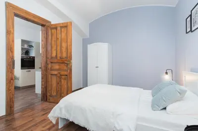 a bedroom with a white bed and a wooden door at Prague Days - Modern Apartments just 7 min from Wenceslas Square in Prague