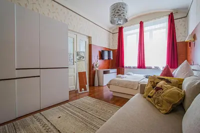 a living room with a couch and a bedroom with red curtains at Central 2BDR flat behind Museum in Prague