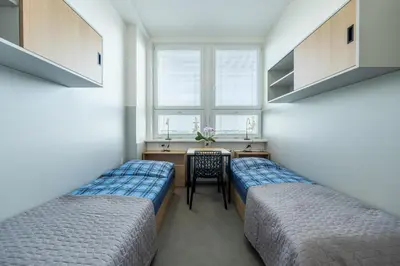 two beds in a room with a table and a window at Penzion BIG HOUSE in Prague
