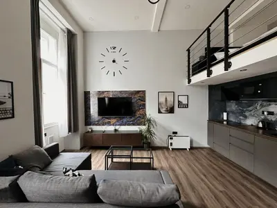 a living room with a couch and a clock on the wall at Grand Viceroy Apartments - Gothic Tower View in Prague