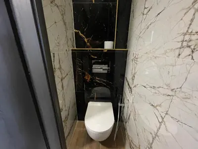 a white toilet in a bathroom with marble walls at Grand Viceroy Apartments - Gothic Tower View in Prague
