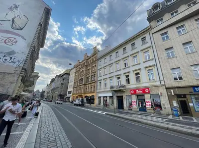 a person walking down a city street with buildings at Contemporary Jindřišská Apartment in Prague