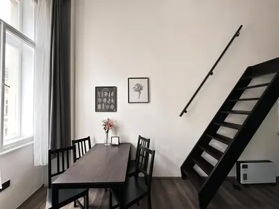 a dining room with a table and chairs and a staircase at Contemporary Jindřišská Apartment in Prague