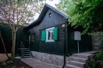 a black house with green shutters and a window at Chata nad Kocábou in Štěchovice