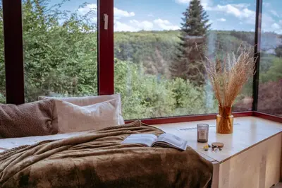 a bed with a book on a table next to a window at Chata nad Kocábou in Štěchovice