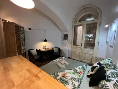 a living room with a bed and a table and a desk at Fun Tiki Vibe Apartment / Charles Bridge / Netflix in Prague