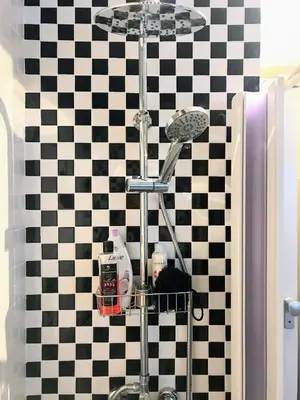 a man sitting in a bathroom in a black and white checkered wall at Fun Tiki Vibe Apartment / Charles Bridge / Netflix in Prague