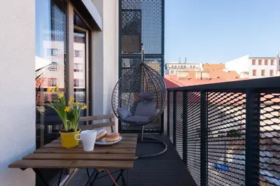 a balcony with a table and a rattan chair at Loft spacious apartments in Prague in Prague