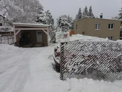 a car covered in snow in front of a garage at DIVADELNÍ PENZION in Bukovany