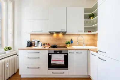a kitchen with white cabinets and a sink at Prague Days - Apartment with Balcony & Garage near Vltava River in New Town in Prague