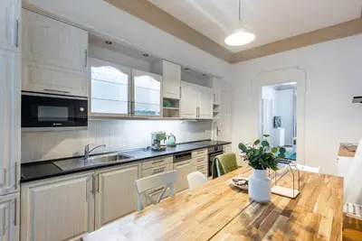 a kitchen with white cabinets and a wooden table at 2BDR Old Town Square Apartments w Fast Wi-Fi in Prague
