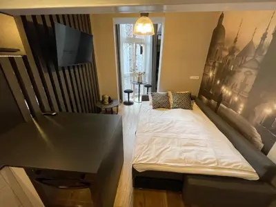 a living room with a bed and a tv at Holec Apartments in Prague