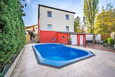 a large blue swimming pool in front of a house at Báječné ubytování ve vile s bazénem a terasou v praze in Prague